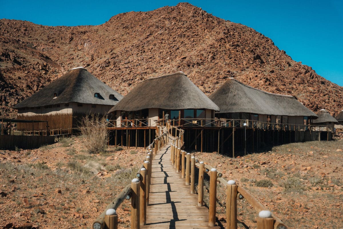 Chambre de lodge ouvrant sur le désert namibien à travers une grande baie vitrée