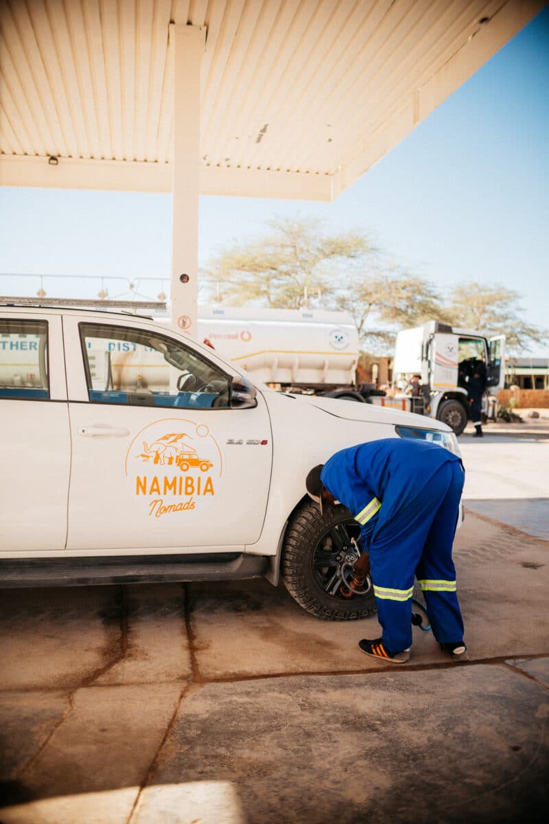 Personne réparant un pneu de 4×4 au bord d'une route en Namibie