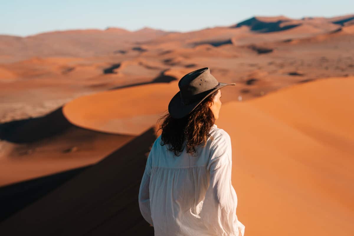 Femme en blanc de dos contemplant les dunes rouges de Sossusvlei