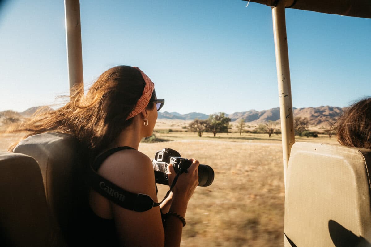 Femme photographiant depuis un véhicule de safari dans la savane