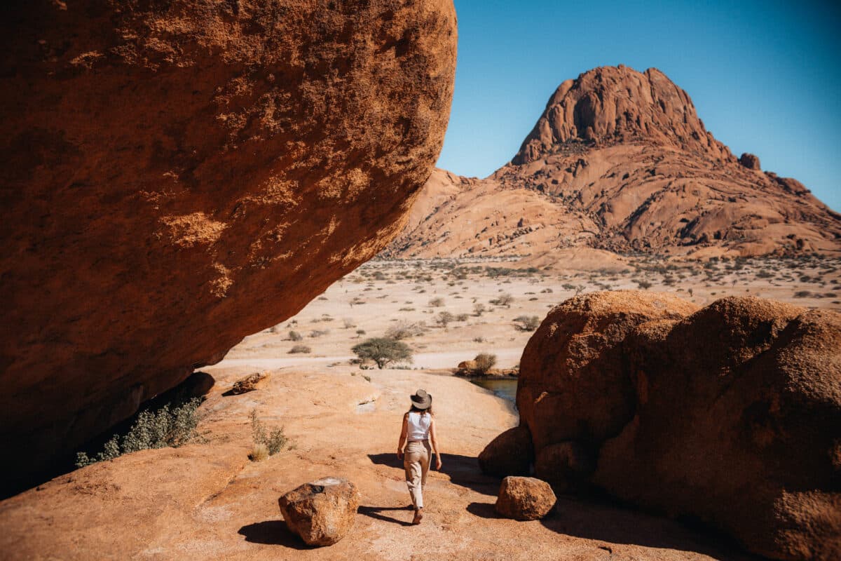 Femme en robe de dos contemplant les pics de Spitzkoppe