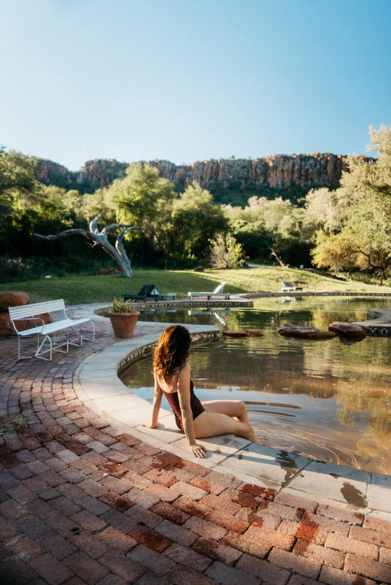 Femme assise au bord d'un bassin naturel dans un lodge