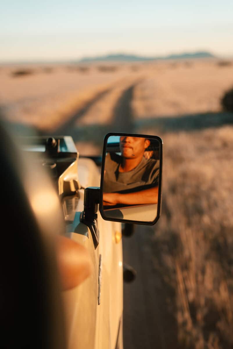 Reflet du guide dans le rétroviseur d'un véhicule lors d'un game drive en Namibie