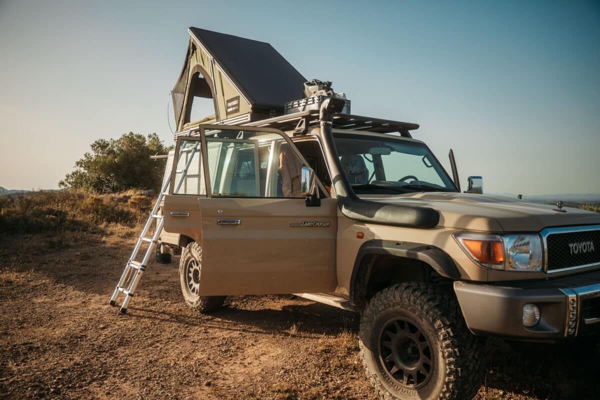 4x4 équipé d'une tente de toit face aux sommets lors d'un road trip dans les Pyrénées espagnoles