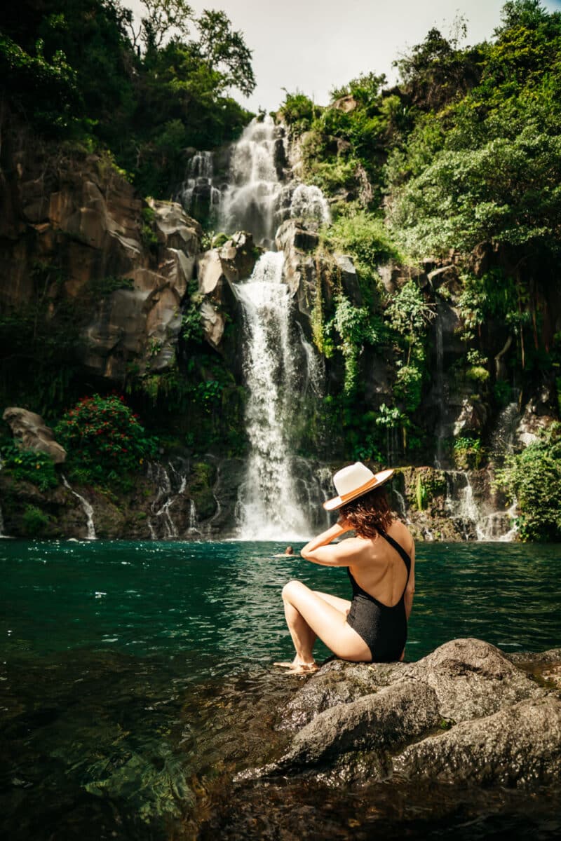 Femme en maillot de bain au pied d’une cascade, dans un bassin naturel de La Réunion